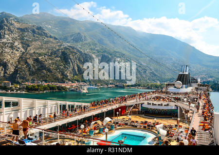 Les passagers de croisière profitez de la piscine et terrasse sur leur bateau de croisière comme ils naviguer loin de la ville côtière de Kotor, Monténégro, sur la côte Adriatique. Banque D'Images