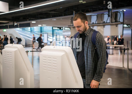 Beau jeune homme barbu faisant l'enregistrement au comptoir de la compagnie aérienne machine Banque D'Images