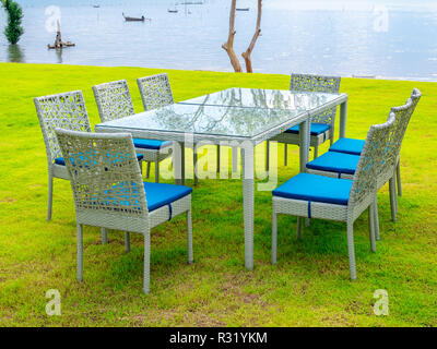 Table à manger avec fond marin. Table et chaises modernes avec plaque bleue, table à manger sur la pelouse verte près de la mer. Banque D'Images