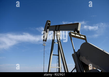 Cric de pompe de site de puits de production de pétrole brut et ciel bleu et nuages dans le bassin de Riber de poudre du Wyoming, États-Unis Banque D'Images