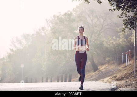 Beau portrait femme blanche court le long de la route dans la lumière du soleil du matin Banque D'Images