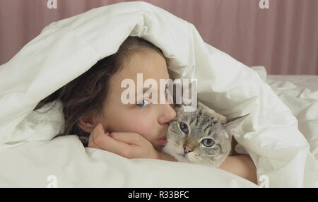 Happy teen girl baisers et des pourparlers avec Thai cat in bed Banque D'Images