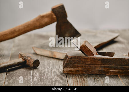 Vue en gros peu de la construction en bois, marteau et hache sur table en bois sur fond gris Banque D'Images