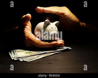 La protection de l'épargne. Protéger les mains tirelire avec des dollars. La protection de l'épargne. Banque D'Images