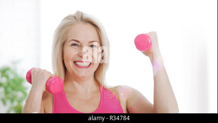 Happy young woman lifting dumbbells à la maison dans la salle de séjour Banque D'Images