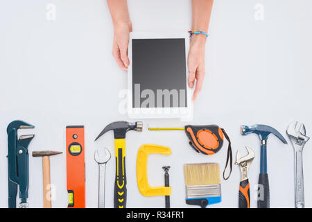 Cropped shot of woman using tablet avec divers outils se trouvant sur blanc Banque D'Images