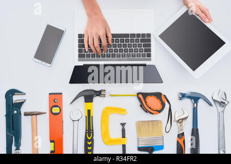 Cropped shot of woman using gadgets avec divers outils se trouvant sur blanc Banque D'Images