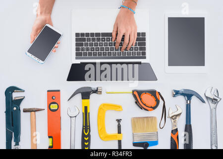 Cropped shot of woman en utilisant les appareils avec divers outils se trouvant sur blanc Banque D'Images