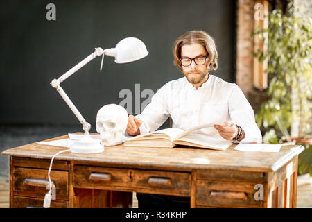 Portrait d'un jeune beau médecin ou étudiant en médecine en uniforme pendant le travail ou l'étude au bureau ou salle de classe Banque D'Images