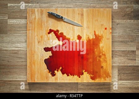 Le sang et le couteau sur la grande planche à découper en bois Banque D'Images