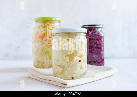 Trois pots de verre avec un assortiment de légumes fermentés debout sur fond blanc Banque D'Images