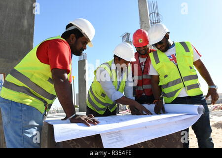 Les hommes avec les Bleus en main sont travaillant dans l'industrie de la construction et de porter un casque et gilet de sécurité, ils restent ensemble sous le ciel bleu et s Banque D'Images