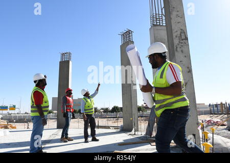 Les hommes avec les Bleus en main sont travaillant dans l'industrie de la construction et de porter un casque et gilet de sécurité, ils restent ensemble sous le ciel bleu et s Banque D'Images