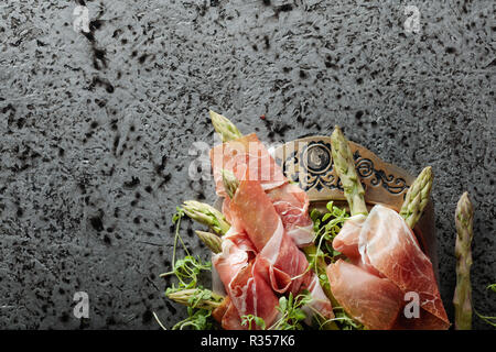 Enveloppé dans le prosciutto avec asperges salade de cresson sur un fond de métal. Vue de dessus, copiez l'espace pour votre texte. Banque D'Images