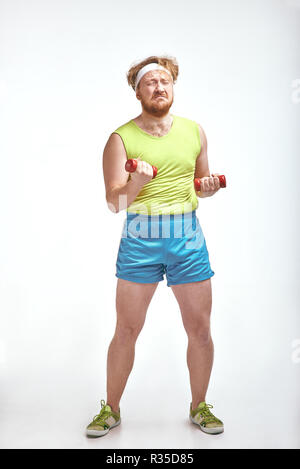 Aux cheveux rouges, barbu, joufflu l'homme est maintenant les dumbbells Banque D'Images