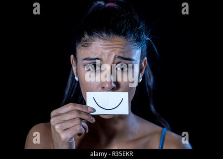 Close up portrait dramatique de femme triste de se cacher sa dépression avec sourire peint sur papier dans l'émotion humaine souffrant en silence la dépression iso concept Banque D'Images