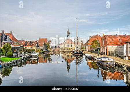 Hindeloopen, aux Pays-Bas, le 4 novembre 2018 : et d'écluse écluse adjacente keepers house, pont, bateaux et maisons anciennes de refléter dans le miroir-comme wate Banque D'Images