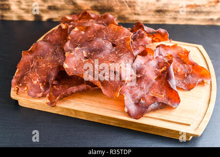 Émincé de jambon fumé et séché sur bac de chêne de petits cristaux de sel visible sur la viande. Banque D'Images