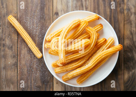 Churros espagnole traditionnelle avec du sucre blanc dans un plat sur une table en bois rustique. Vue d'en haut Banque D'Images