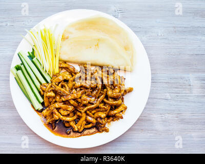 La cuisine chinoise plat - Vue de dessus plaque blanche avec de fines tranches de porc dans la sauce de soja frit servi avec des petits oignons, concombres frais et des crêpes (Peking Banque D'Images