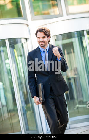 Young businessman jubilation devant un bâtiment d'entreprise Banque D'Images