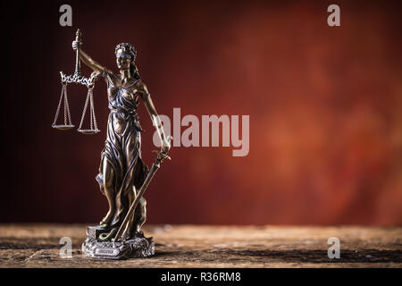 Dame Justicia tenant un sabre et l'échelle figurine en bronze sur table en bois. Banque D'Images