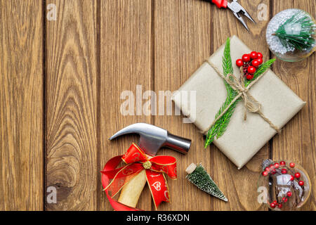 Joyeux Noël Outils pratiques concept cadeau de Noël. Marteau, pinces, boîte cadeau et décorations de Noël sur fond de bois. Vue de dessus avec l'exemplaire Banque D'Images