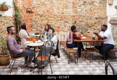 Foule diversifiée de conversations au café branché des boissons dans une cour intérieure Banque D'Images