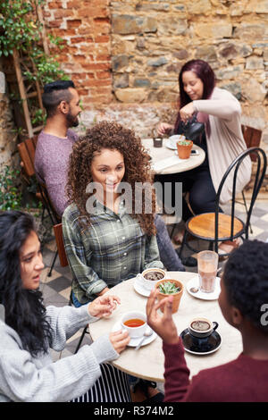 Souriante jeune femme chat avec des amis dans un café courtyard Banque D'Images