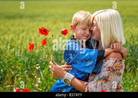 Maman avec son fils dans une magnifique prairie. Le garçon embrasse sa mère fermement et amoureusement. Banque D'Images