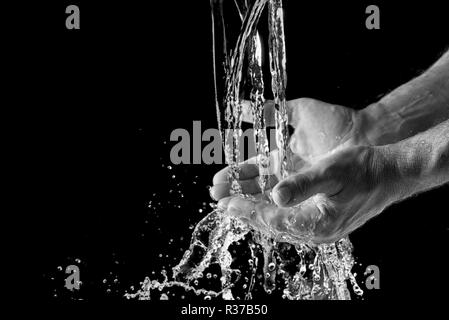 Les projections d'eau dans la main de l'homme contre un fond noir avec copie espace de discussion, Banque D'Images