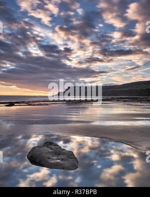 Un lever de soleil sur la mer spectaculaire vers les falaises à Ravenscar Boggle Hole, Robin Hood's Bay, près de Whitby, North Yorkshire Banque D'Images