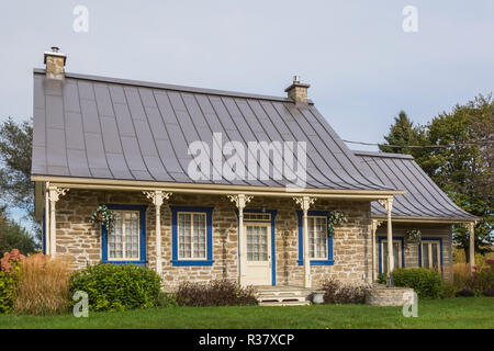 Vieux chalet en pierre de style 1820 façade de maison avec garniture bleue et marron feuille à joint debout metal roof plus journal empilées Banque D'Images