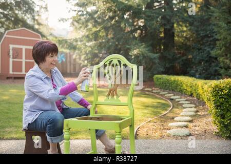 Une femme mûre artiste la restauration d'un fauteuil. Banque D'Images