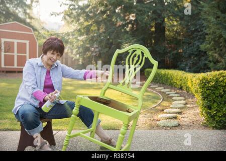 Une femme mûre artiste la restauration d'un fauteuil. Banque D'Images