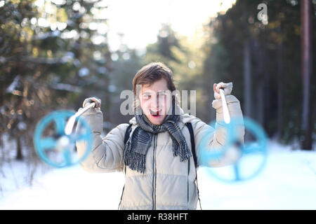 La skieuse de crier avec poteaux de fond aux beaux jours d'hiver dans la forêt (accent sur la jeune homme) Banque D'Images