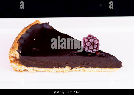 Boulangerie Pâtisserie tarte au chocolat à la framboise sur le dessus servi sur plaque blanche avec fond noir isolé Banque D'Images