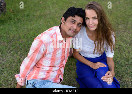 Multi Ethnic couple sitting on the prairie dans l'amour à la gr Banque D'Images