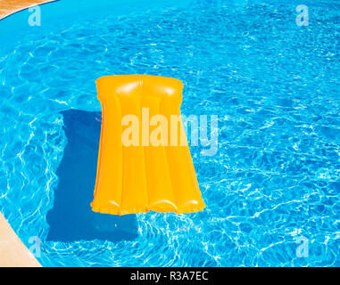 Matelas gonflable Orange flottant dans la piscine Banque D'Images