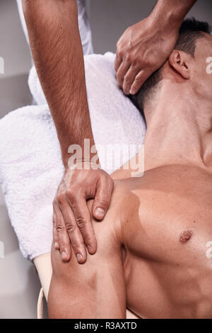 Deux jeune homme, 20-29 ans, physiothérapie sportive à l'intérieur en studio, séance photo. Le massage kinésithérapeute mans dos. Banque D'Images