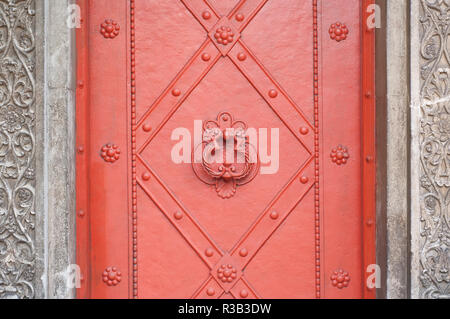 Porte métallique rouge vintage avec porte-marteau dans un cimetière, détail Banque D'Images