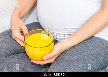 Pregnant woman holding a mug avec du jus d'orange Banque D'Images