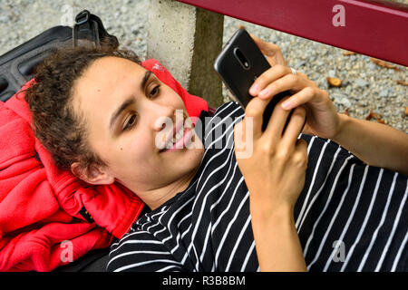 Jeune femme à l'aide, looking at smartphone, téléphone mobile, Allemagne Banque D'Images