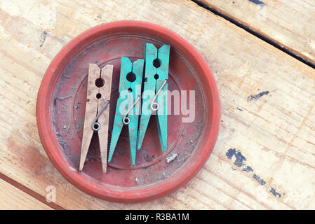 Trois vieilles clothespin dans dirty dish sur fond de bois Banque D'Images