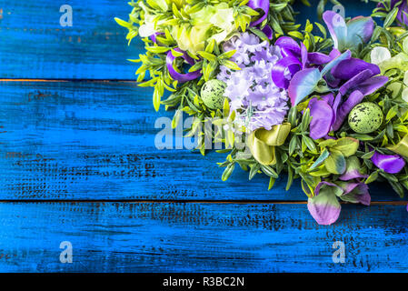 Couronne de Pâques printemps avec des oeufs, buis et fleurs sur fond de bois. Banque D'Images