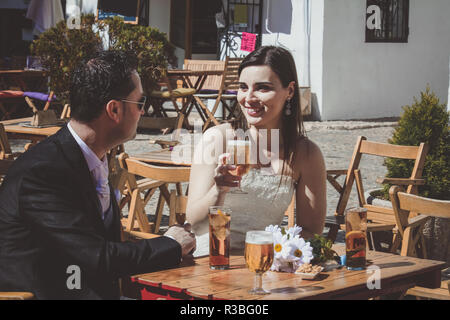 Jeune couple de Mariés le jour de leur mariage, de détente dans un bar et boire une bière Banque D'Images