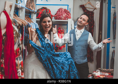 Jeune couple de mariage achat de vêtements dans une boutique. L'épouse, c'est étonné, le marié est désespérée Banque D'Images