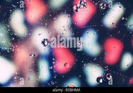Une belle et dynamique des bulles d'huile macro sur l'eau avec un flou de coeurs roses et blancs sur fond noir Banque D'Images