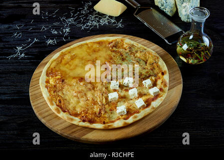 Pizza au fromage chaud assortiment. Les fromages frais, une râpe, l'huile d'olive avec des herbes et des épices dans une cruche en verre sur une planche de bois. Banque D'Images