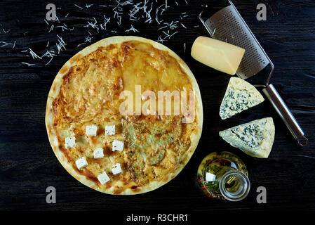 Pizza au fromage chaud assortiment. Les fromages frais, une râpe, l'huile d'olive avec des herbes et des épices dans une cruche en verre sur une planche de bois. Banque D'Images